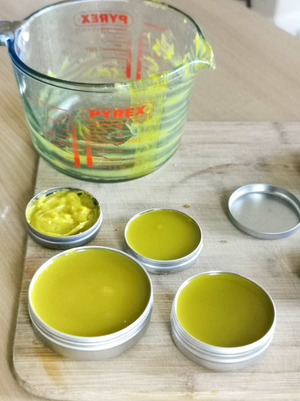 DIY calendula salve being poured into recycled tins.