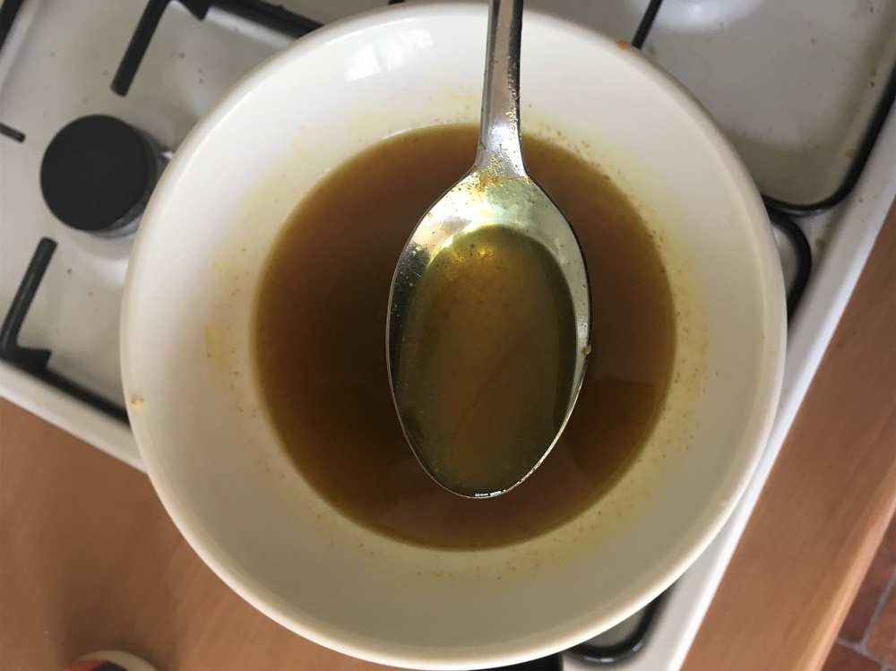 A spoon held over the melted contents of a makeshift double boiler.