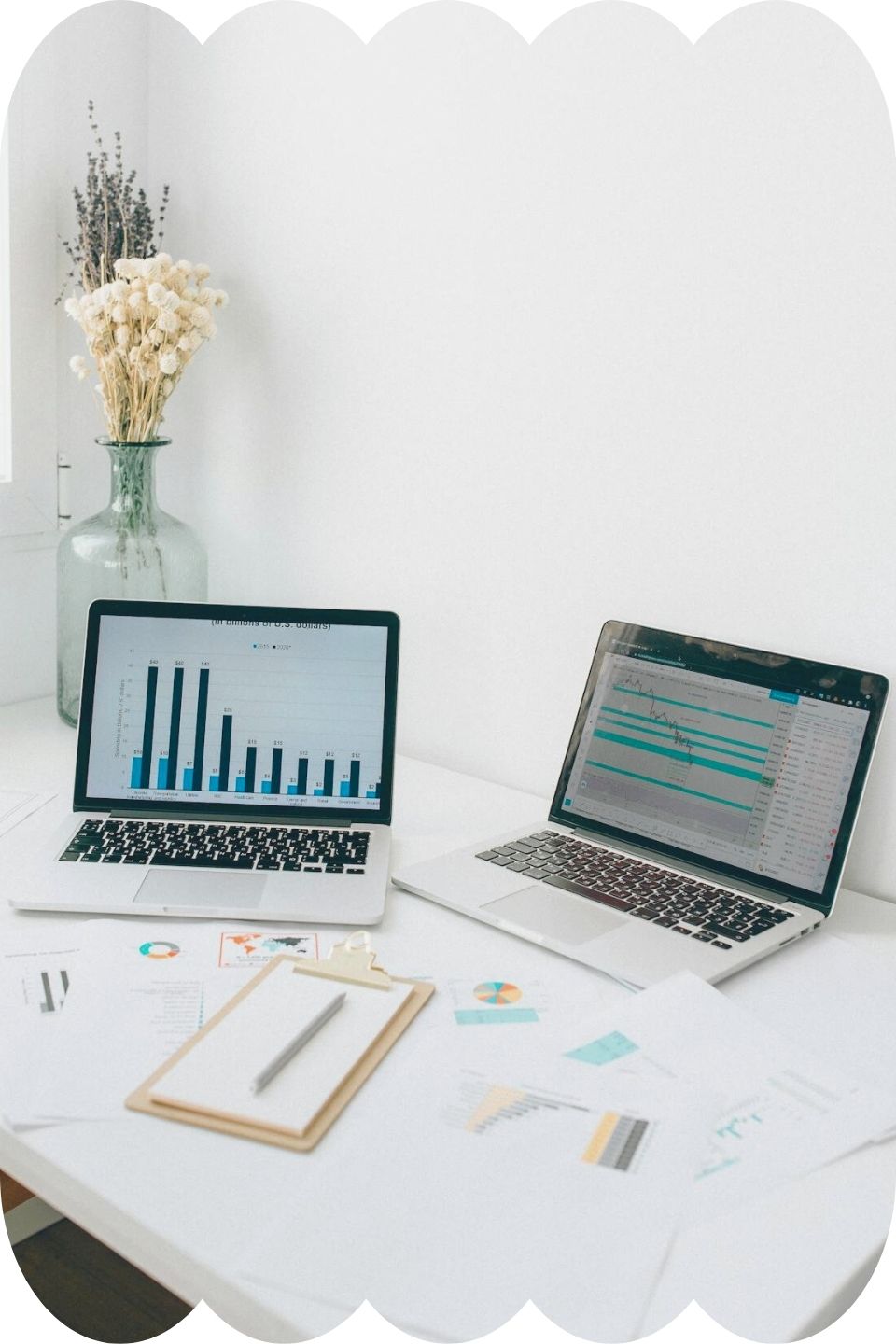 Two laptops sitting atop a white desk, both showing graphics of data analytics for small business.